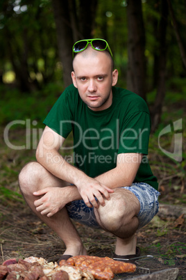 Man sitting near barbecue fire