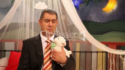 Sad man sitting inside of playpan with toy lamb