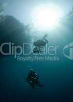 Two scuba divers in shallow water with sunrays