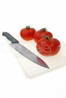 Cutting white plastic board with a knife and tomato