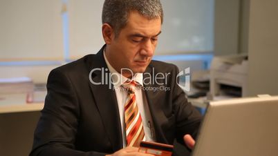 Businessman with credit card, using laptop