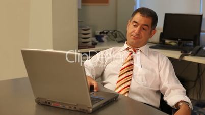 Tired businessman using laptop in office
