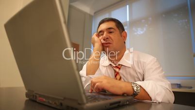 Sleepy businessman using laptop in office