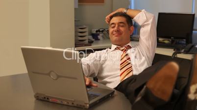 Relaxed businessman working on laptop in office