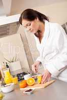 Young woman cutting orange for breakfast in kitchen
