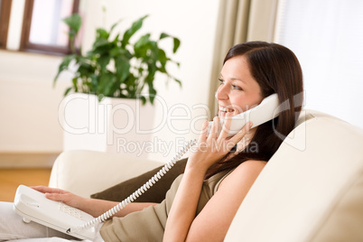 On the phone home: Young woman calling in lounge