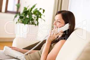 On the phone home: Young woman calling in lounge