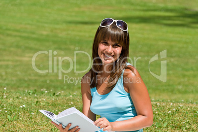 Smiling young woman read book in park
