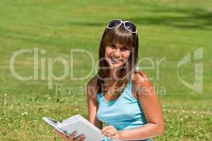 Smiling young woman read book in park