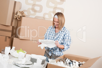 Moving house: Happy woman unpacking dishes