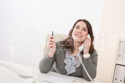 Smiling young business woman on phone at office