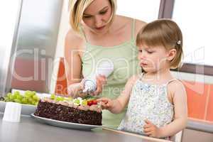 Mother and child with chocolate cake in kitchen