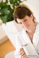 Young woman in white bathrobe with coffee