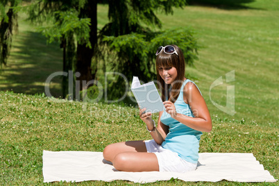 Smiling young woman read book in park