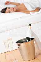 Champagne in ice bucket, woman sleeping in background