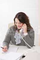 Smiling young woman on the phone at office