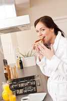 Young woman eating toast for breakfast in kitchen