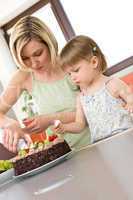 Mother and child with chocolate cake in kitchen