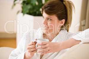 Young woman in white bathrobe with coffee