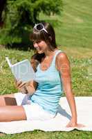Smiling young woman read book in park