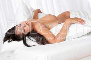 Naked woman sleeping in white bed