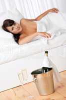 Naked woman in white bed with champagne