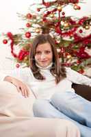 Young woman sitting in front of Christmas tree