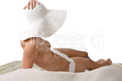 Topless woman with hat sunbathing on beach