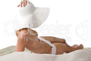 Topless woman with hat sunbathing on beach