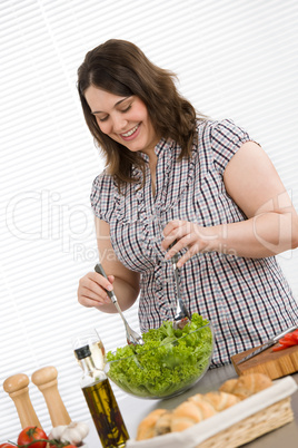 Cook - Plus size happy woman preparing salad in kitchen