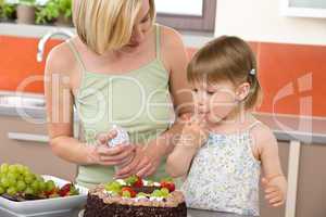 Mother and child with chocolate cake in kitchen