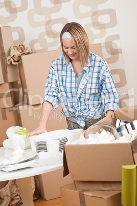 Moving house: Happy woman unpacking dishes