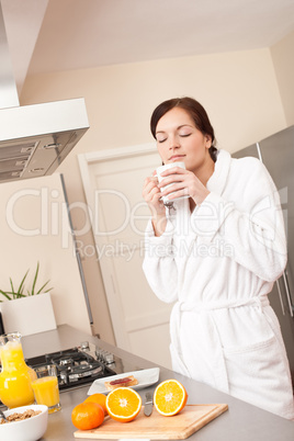 Young woman enjoying coffee and breakfast in kitchen
