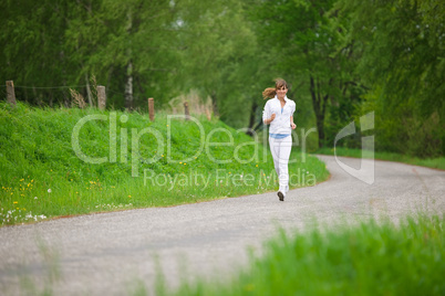 Jogging - sportive woman running on road in nature