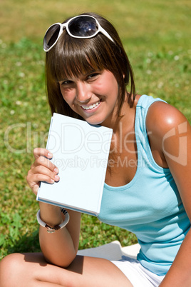 Happy young woman with book in park