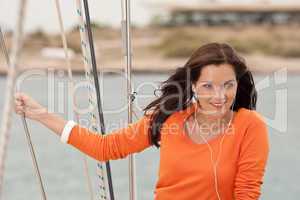 Attractive woman standing on sailing boat with headphones