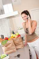 Young smiling woman with groceries in the kitchen