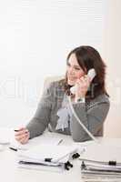 Smiling young business woman on phone at office