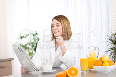 Breakfast - Smiling woman reading newspaper in kitchen