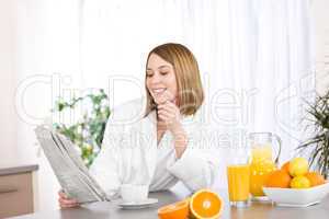 Breakfast - Smiling woman reading newspaper in kitchen