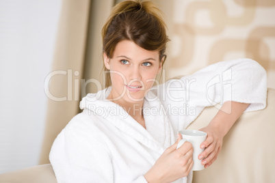 Young woman in white bathrobe with coffee