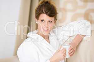 Young woman in white bathrobe with coffee