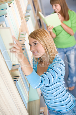 Student in library - two woman choose book