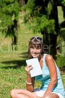 Happy young woman with book in park