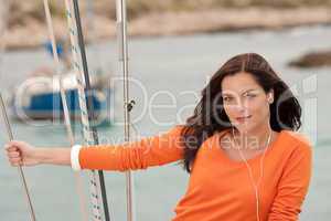 Attractive woman standing on sailing boat with headphones