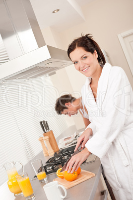 Smiling woman cutting oranges in the kitchen