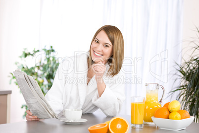 Breakfast - Smiling woman reading newspaper in kitchen