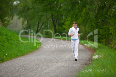 Jogging - sportive woman running on road in nature