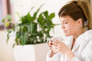 Young woman in white bathrobe with coffee
