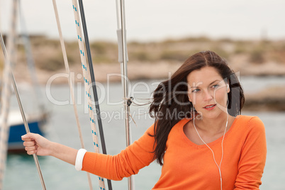Attractive woman standing on sailing boat with headphones
